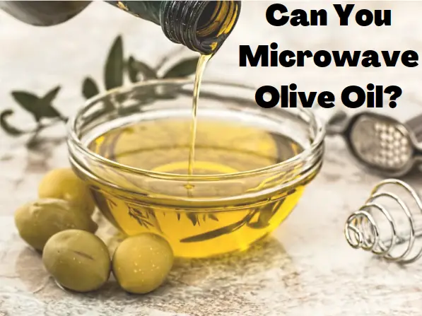 Several green olives sitting beside a small glass bowl of olive oil