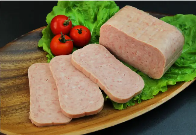 Sliced spam on a plate with tomatoe and lettuce